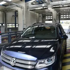 Coche oscuro en una estación de inspección técnica de vehículos (ITV) con un técnico al fondo.